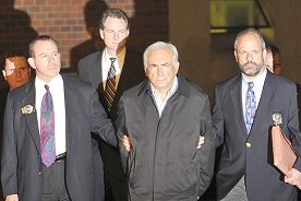 Arrestation de Dominique Strauss-Kahn, main menottées dans le dos, encadré de deux policiers new-yorkais, sortant du commissariat d'Harlem - Cliquer pour AGRANDIR